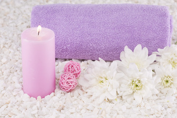 Obraz na płótnie Canvas Spa. Still life. Towel rolled up in a roll, a pink candle, white chrysanthemum flowers.