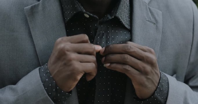 Closeup portrait of young african postgraduate student in classical suit buttoning shirt