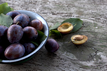 Obraz premium Ripe plums in plate on wooden background