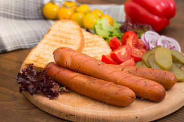 Food set for hot dog, sausage, canned cucumbers, lettuce leaves, tomatoes, onions, croutons on the wooden background. Close-up. Top view
