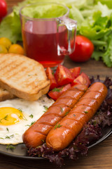 English breakfast - toast, egg, sausages and vegetables salad. Wooden rustic background. Close-up. Top view