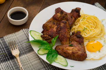 Fried chicken wings with spaghetti. Wooden background. Close-up. Top view