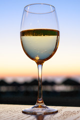A glass of white wine at the seaside sunset background