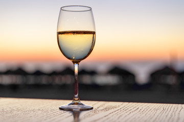 A glass of white wine at the seaside sunset background