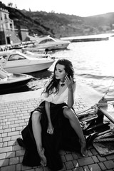 Beautiful girl walking on the pier by the sea near the yacht, boats in the blue long dress