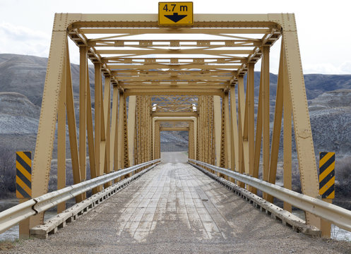 Yellow steel bridge on gravel road