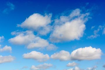 Low angle view of medium size white cumulus clouds against deep blue sky by sunny weather.