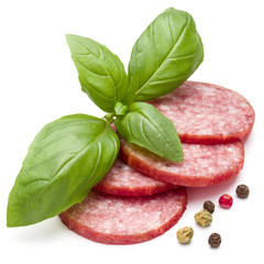 Salami smoked sausage slices, basil leaves and peppercorns isolated on white background cutout