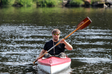 Junger Mann im roten Kajak beim Paddeln am Fluss