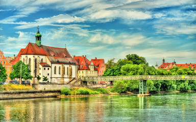 St. Oswald Church with Eiserner Steg bridge across the Danube River in Regensburg, Germany