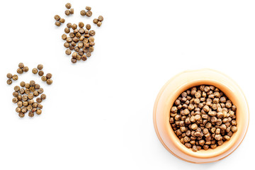 bowl full and overflowing with dry pet - dog food bits and paw prints on white background top view mock-up