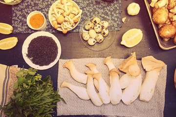 Group of raw ingredients for preparing vegetarian dinner.Oyster mushrooms, champignons, honey mushrooms, quail eggs, arugula, black sesame, lemon. Healthy food concept