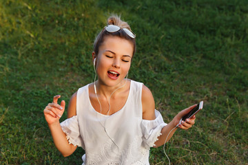 Happy girl listening music on phone with headphones and sign. Audio from app fo smartphone. Young...