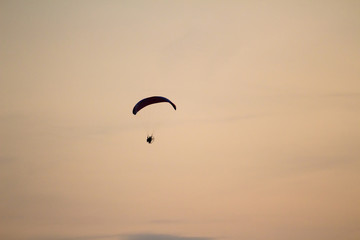 A man is flying on a paraglider over the sea and the beach