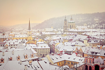 old European city in the early winter morning, roofs of houses are covered with snow, over the city spikes of temples tower