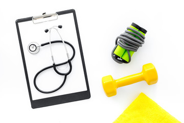 Sport and health. Fitness. Dumbbells and stethoscope on white background top view