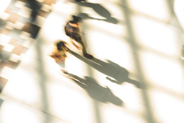 Silhouettes of two people walking in a public building hall top view. Motion blur technique of low...