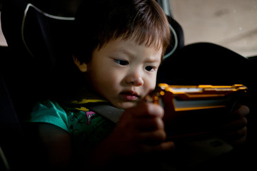asian children watching tablet in car / playing phone and looking at cartoon