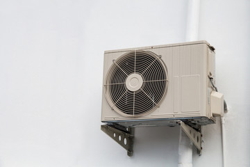 Air compressor on wall pedestal with siding factory wall background.