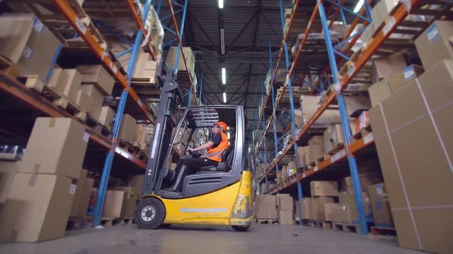 forklift operator puts boxes with goods on the metal racks