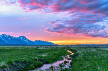 Sunset Mountain Meadow - Colorful spring sunset at a green mountain field with a winding stream...
