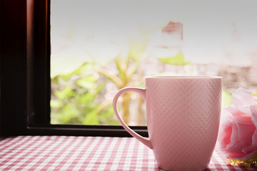 Obraz na płótnie Canvas Hot coffee and sweet pink roses on the table with Scottish tablecloth with morning light attached to windows in Thailand