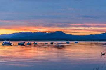 Obraz premium Sunset Jackson Lake - Spring sunset lights up cloudy sky over a quiet bay of Jackson Lake in Grand Teton National Park, Wyoming, USA. 