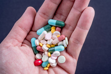 Variety Drug in hand on black background.  Colorful Medicines. Healthcare or addiction concept