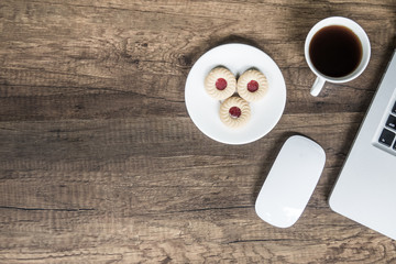 Top view home office table with laptop, coffee and cookie on wooden table. Modern office top view at home. New life style. Concept : business and office.