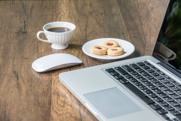 Top view home office table with laptop, coffee and cookie on wooden table. Modern office top view at home. New life style. Concept : business and office.