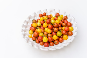Garden harvest of yellow and red cherry tomatoes on white tray