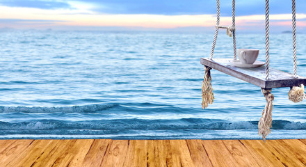 Empty wood  top table and coffee cup on wood swing  with sea  Background. for product display montage.