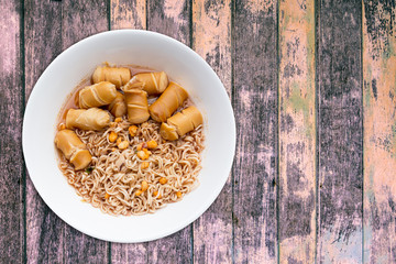Instant noodles in bowl on wood background top view.