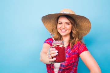 Sexy cute girl posing in studio, drinking fruit juice or cocktail on blue background and copy space