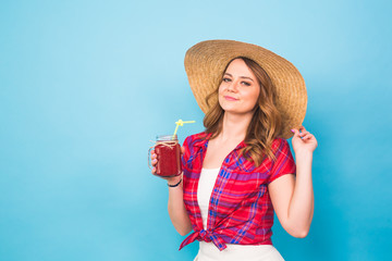 smiling woman drink red juice. studio portrait with blue background and copy space