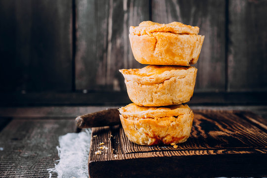 Fresh australian meat pie on the wooden table closeup with copy space, rustic style