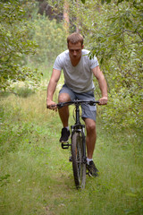 Naklejka premium a cyclist on a mountain bike rides through the carriageway along the asphalt road. A healthy lifestyle. A lovable sports hobby