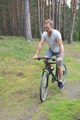 Naklejka premium a cyclist on a mountain bike rides through the carriageway along the asphalt road. A healthy lifestyle. A lovable sports hobby 