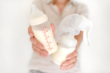 Breast pump and bottle with milk in woman's hand - 169362261