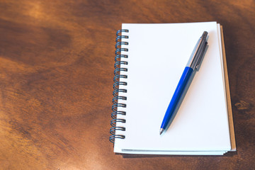 Blank notebook and pen on wooden desk