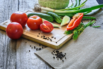 Basket with fresh vegetables (tomatoes, cucumber, chili pepers, dill) on wooden background. Outdoor, in the garden, on the farm. Selective focus, close up. Space for text.