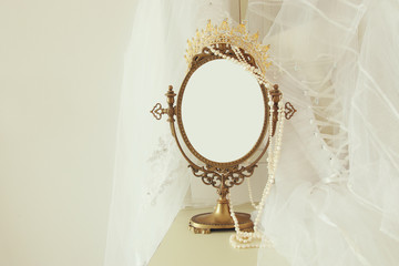 Old vintage oval mirror and beautiful white wedding dress and veil on chair. Copy space for mock up, montage or design layout