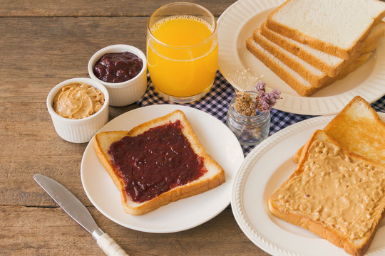 Toast Bread With Homemade Strawberry Jam And Peanut Butter Served With Orange Juice. Homemade Toast Bread With Jam And Peanut Butter On Wood Table For Breakfast. Delicious Toast Bread Ready To Served.