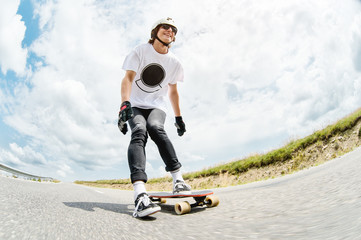 The young Longboarder pushes his foot out on his longboard over the country road