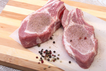 Raw pork chops, spices on cutting board. Ready for cooking.