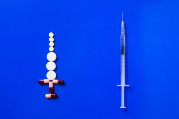 Medical preparations, pills and capsules and syringe lie on blue background. Copy space