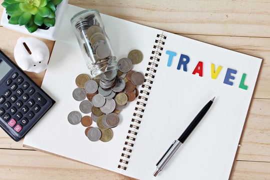 Business, finance, savings or loan concept : Flat lay or top view of word travel on open blank notebook paper and coins scattered from glass jar