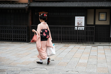 京都の古い街並みを歩く芸者さん