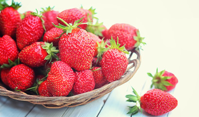 Strawberry in wicker plate on wooden background