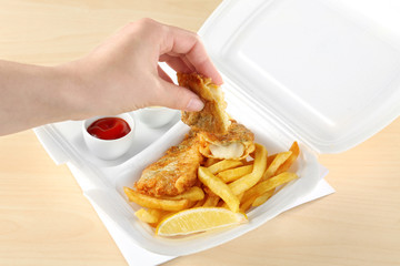 Woman holding a piece of fried fish on wooden background